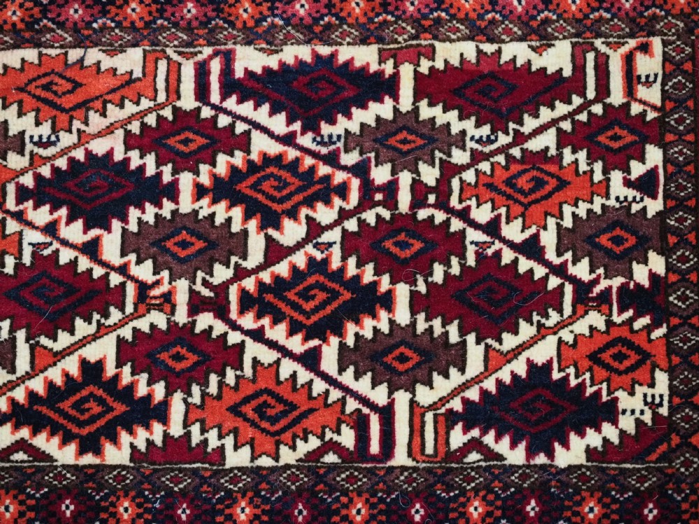 An antique Tekke Turkmen torba face featuring a geometric curled leaf diamond pattern on an ivory field with a thick wool fringe. View VI