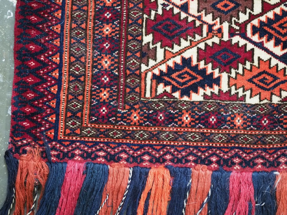 An antique Tekke Turkmen torba face featuring a geometric curled leaf diamond pattern on an ivory field with a thick wool fringe. View VII