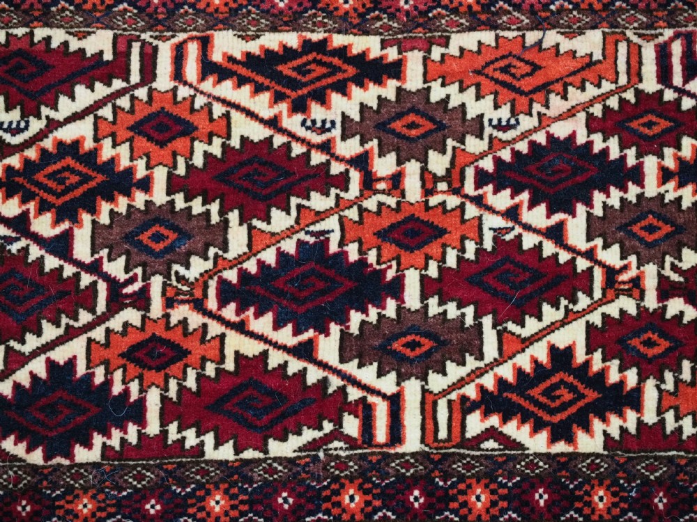 An antique Tekke Turkmen torba face featuring a geometric curled leaf diamond pattern on an ivory field with a thick wool fringe. View VIII