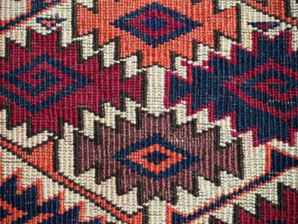 An antique Tekke Turkmen torba face featuring a geometric curled leaf diamond pattern on an ivory field with a thick wool fringe. View X