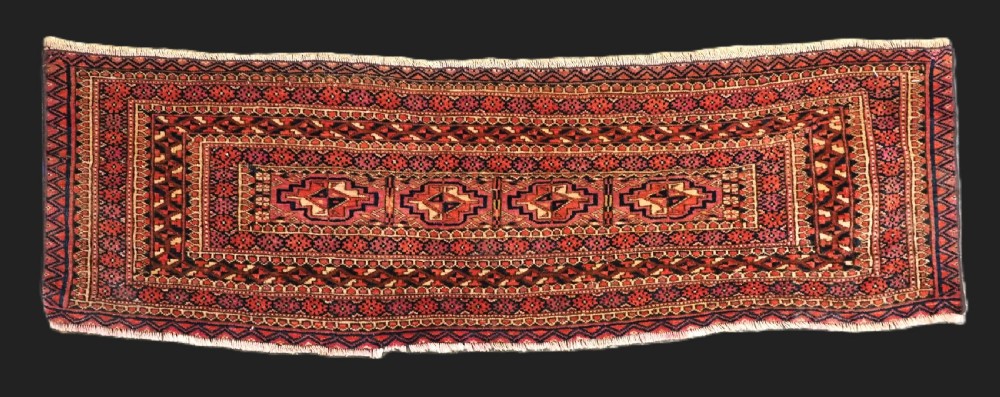 A horizontal hand-knotted wool Tekke Turkmen torba face featuring four central chuval guls enclosed by geometric borders in deep red, navy, and ivory.