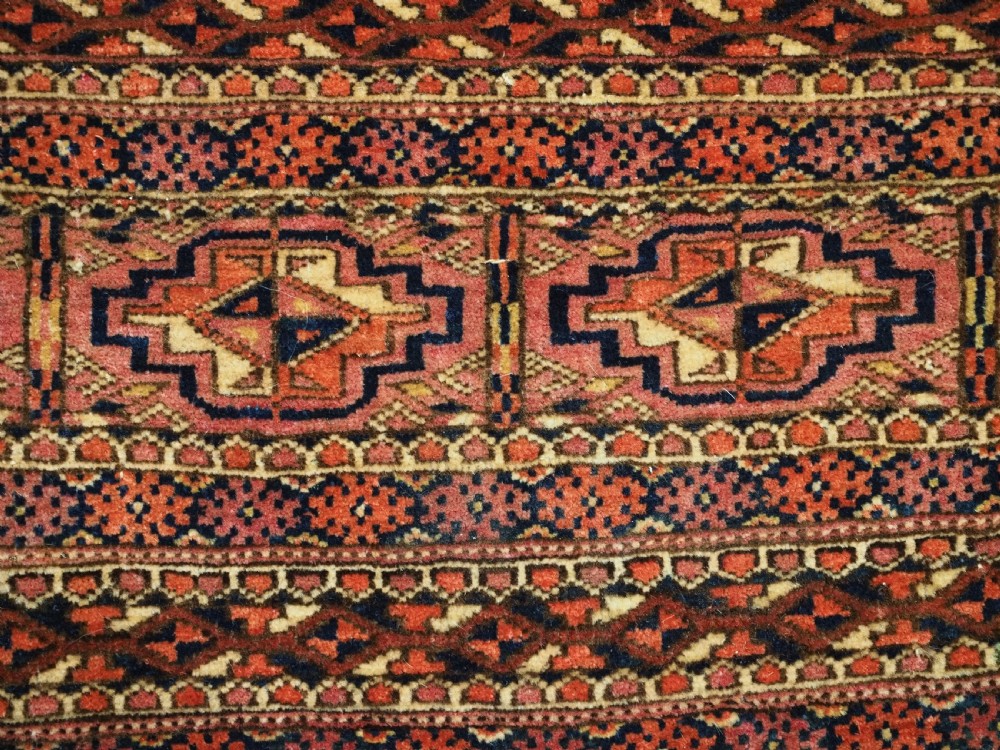 A horizontal hand-knotted wool Tekke Turkmen torba face featuring four central chuval guls enclosed by geometric borders in deep red, navy, and ivory. View VII