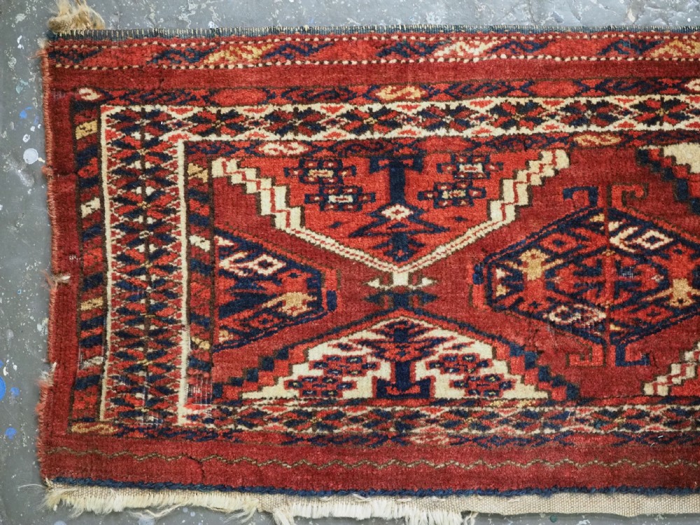 An antique horizontal hand-woven Ersari Turkmen wool torba featuring repeating geometric diamond guls in red, white, and dark blue tones. View II