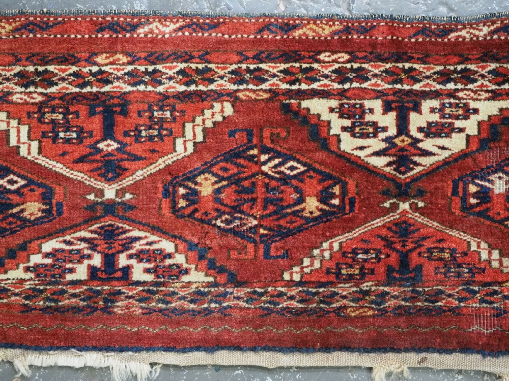 An antique horizontal hand-woven Ersari Turkmen wool torba featuring repeating geometric diamond guls in red, white, and dark blue tones. View III
