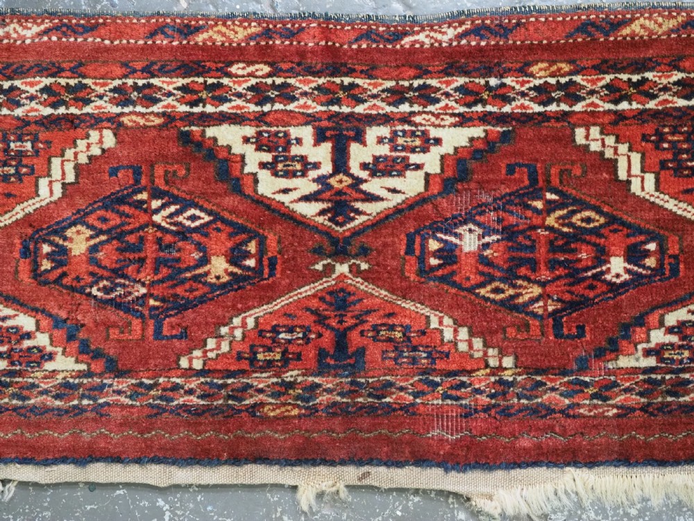 An antique horizontal hand-woven Ersari Turkmen wool torba featuring repeating geometric diamond guls in red, white, and dark blue tones. View IV