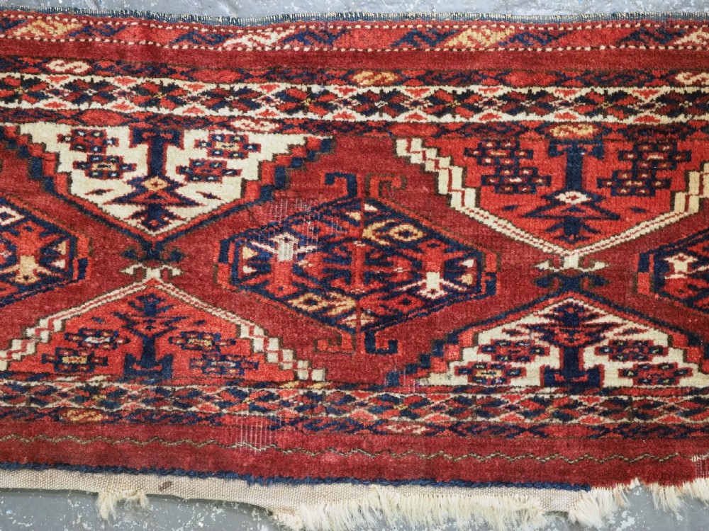 An antique horizontal hand-woven Ersari Turkmen wool torba featuring repeating geometric diamond guls in red, white, and dark blue tones. View V