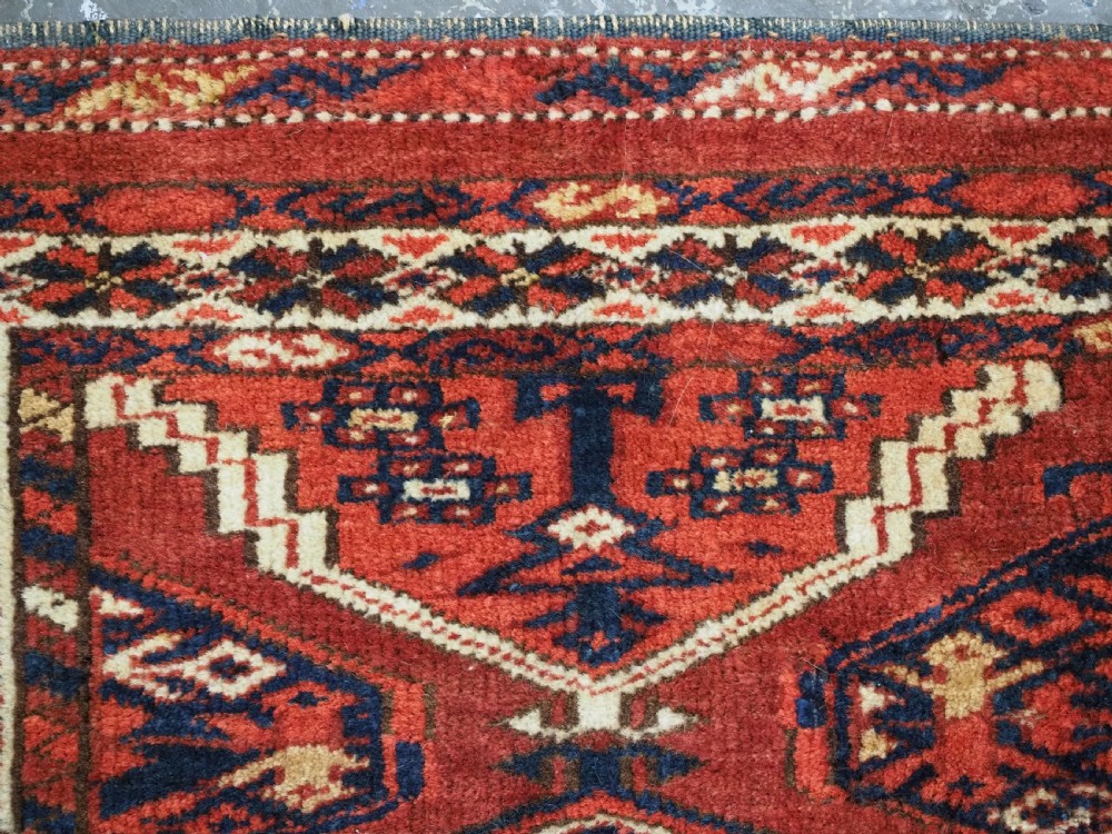 An antique horizontal hand-woven Ersari Turkmen wool torba featuring repeating geometric diamond guls in red, white, and dark blue tones. View VII