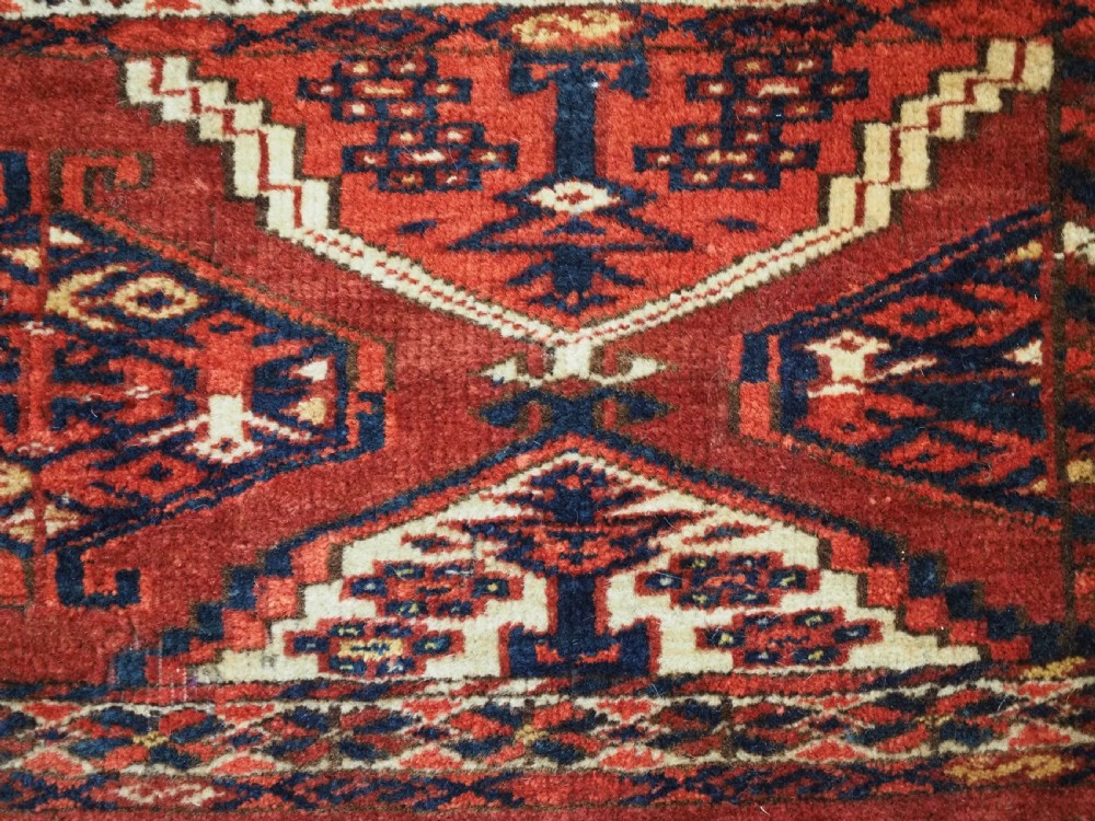 An antique horizontal hand-woven Ersari Turkmen wool torba featuring repeating geometric diamond guls in red, white, and dark blue tones. View IX