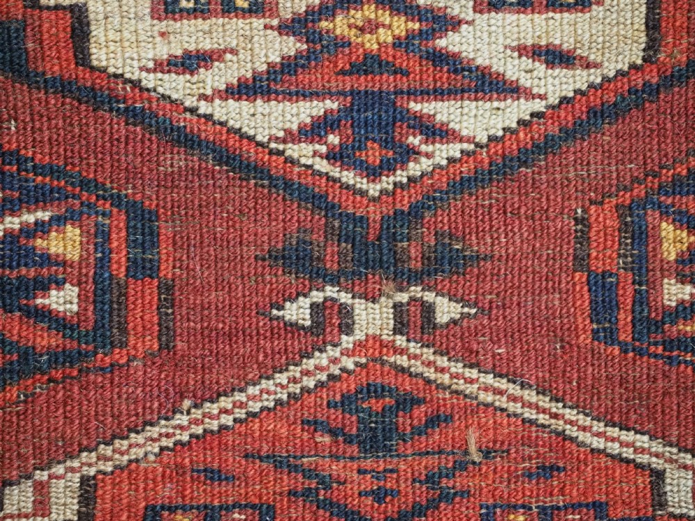 An antique horizontal hand-woven Ersari Turkmen wool torba featuring repeating geometric diamond guls in red, white, and dark blue tones. View X