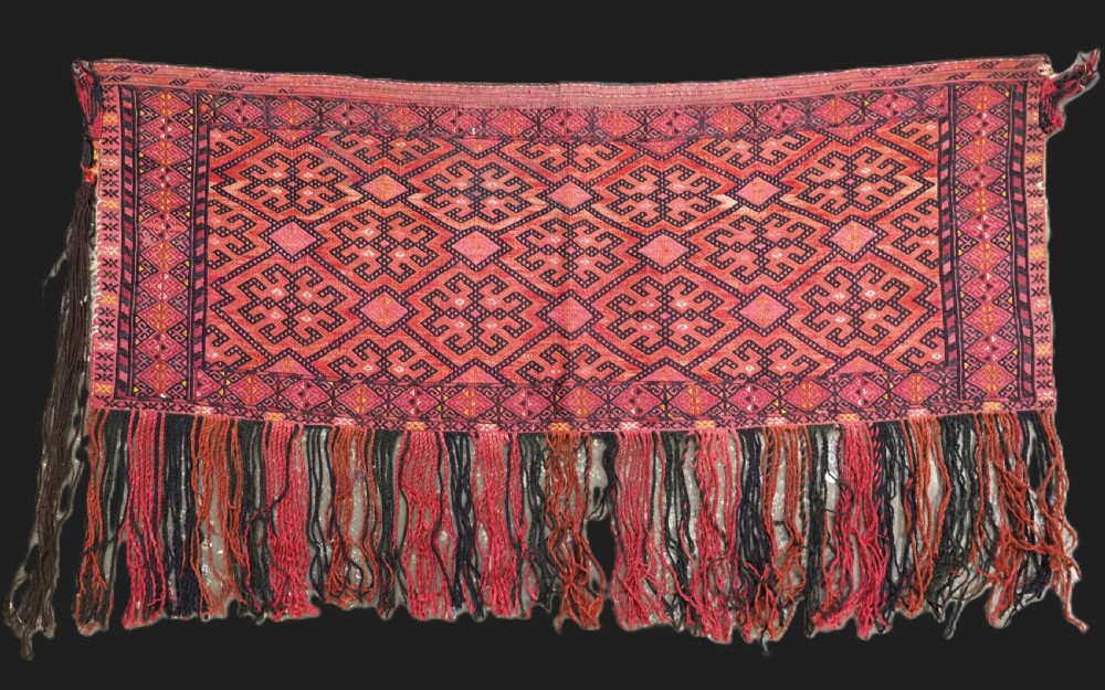 An elongated rectangular Turkmen Ersari torba featuring geometric diamond embroidery in red and dark tones with long fringed tassels along the bottom.