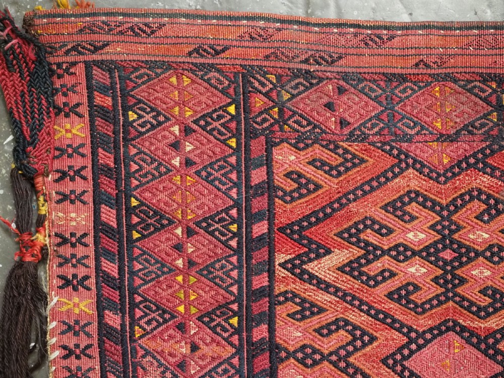 An elongated rectangular Turkmen Ersari torba featuring geometric diamond embroidery in red and dark tones with long fringed tassels along the bottom. View V
