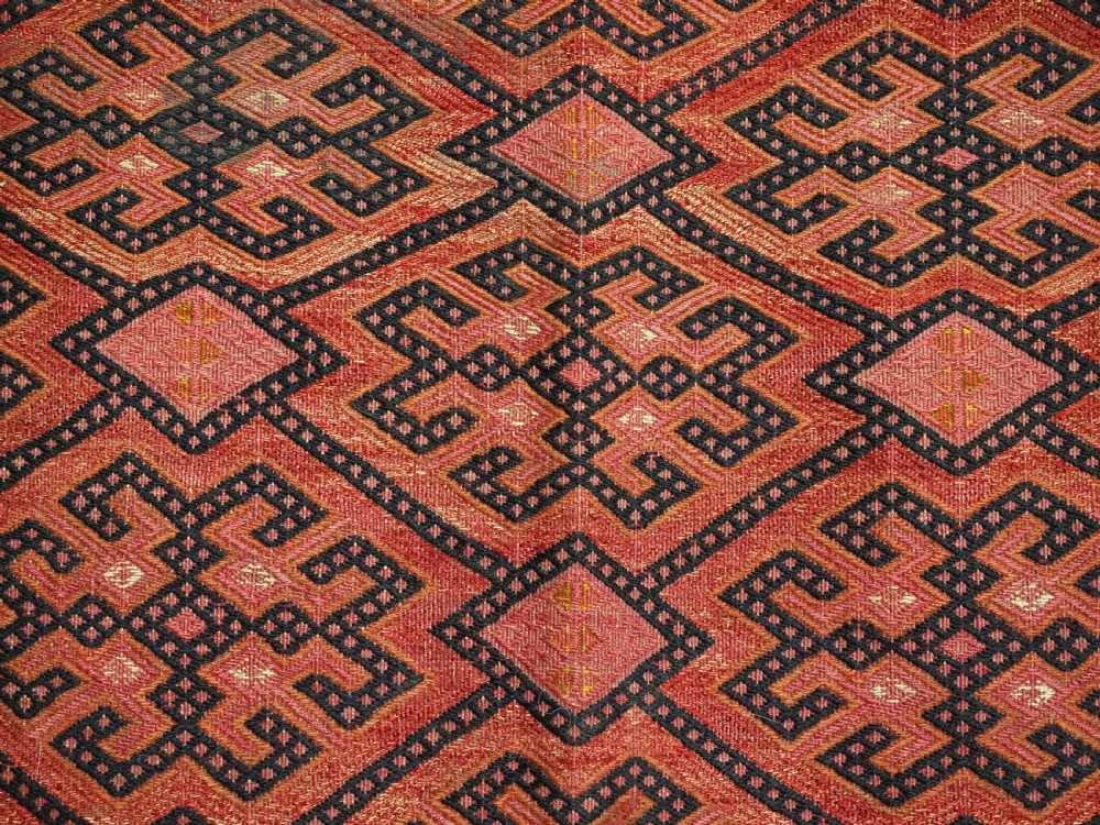 An elongated rectangular Turkmen Ersari torba featuring geometric diamond embroidery in red and dark tones with long fringed tassels along the bottom. View X