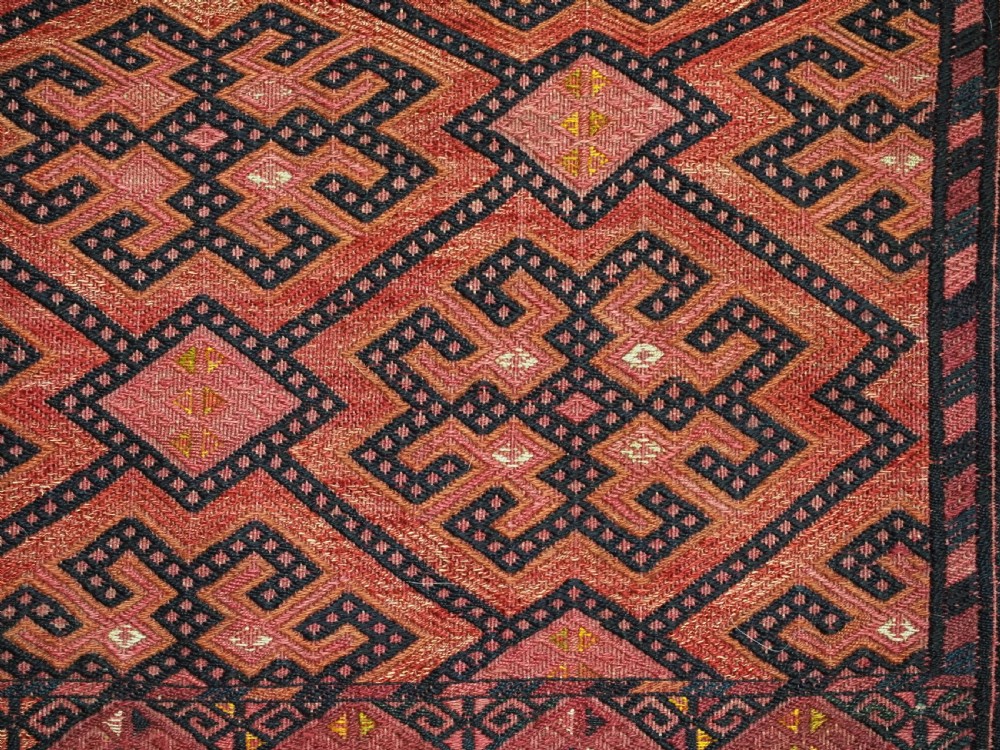 An elongated rectangular Turkmen Ersari torba featuring geometric diamond embroidery in red and dark tones with long fringed tassels along the bottom. View XI