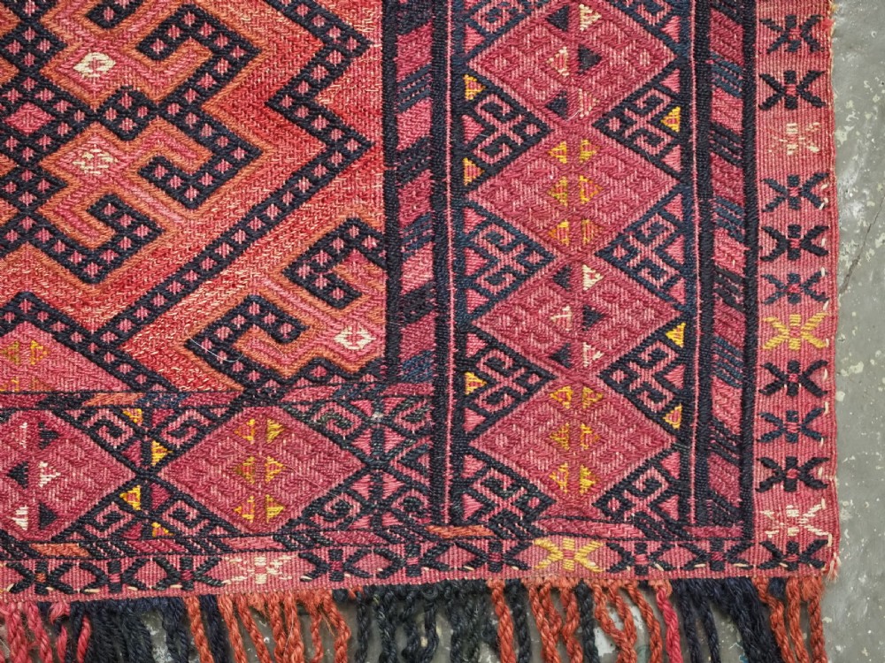 An elongated rectangular Turkmen Ersari torba featuring geometric diamond embroidery in red and dark tones with long fringed tassels along the bottom. View XII