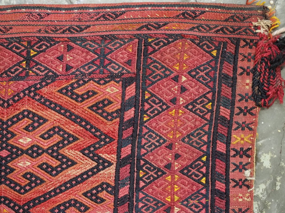 An elongated rectangular Turkmen Ersari torba featuring geometric diamond embroidery in red and dark tones with long fringed tassels along the bottom. View XIII