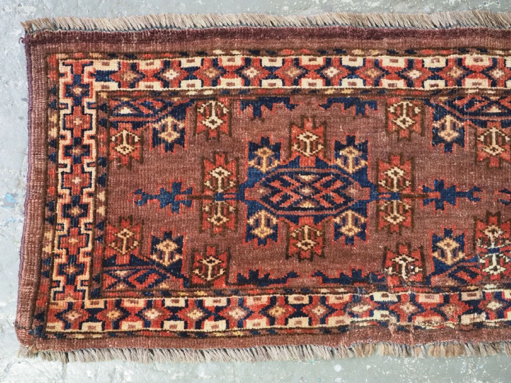 A horizontal rectangular antique wool torba bag face featuring central diamond-shaped Kepse gul motifs in deep red, indigo blue, and ivory framed by a geometric border. View III