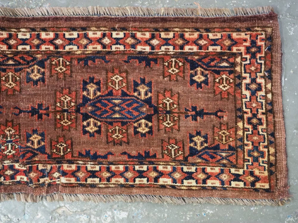 A horizontal rectangular antique wool torba bag face featuring central diamond-shaped Kepse gul motifs in deep red, indigo blue, and ivory framed by a geometric border. View IV