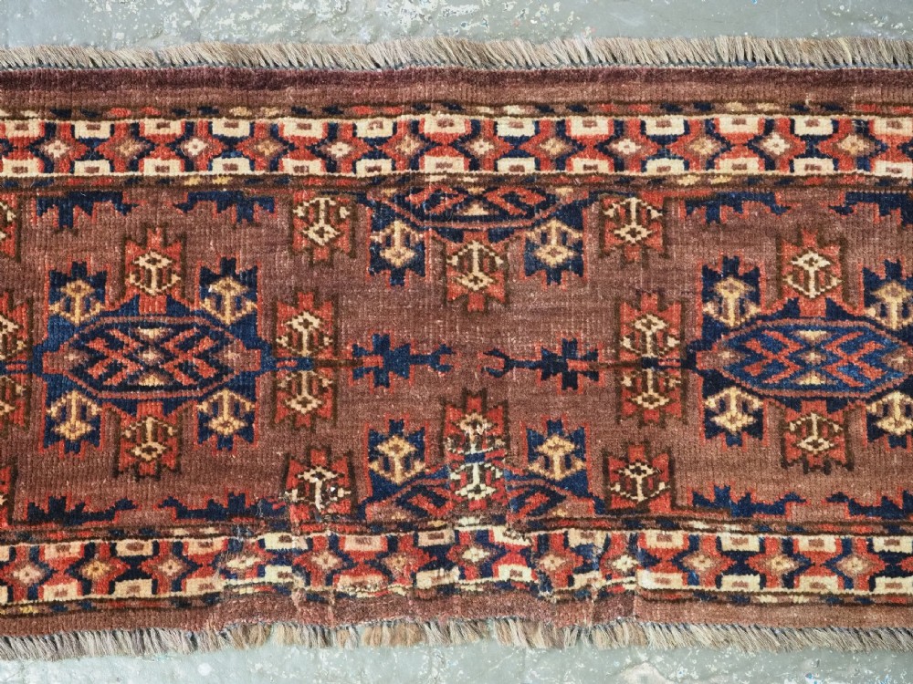 A horizontal rectangular antique wool torba bag face featuring central diamond-shaped Kepse gul motifs in deep red, indigo blue, and ivory framed by a geometric border. View VI