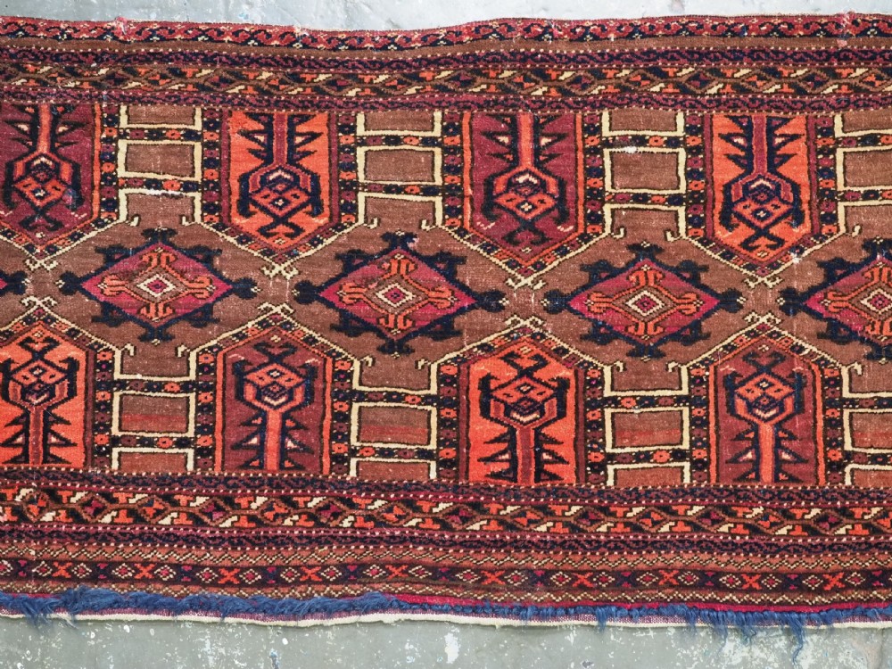 An antique horizontal Saryk Turkmen torba face featuring geometric Kedjebe motifs woven in deep red, dark brown, and cream wool tones. View IV