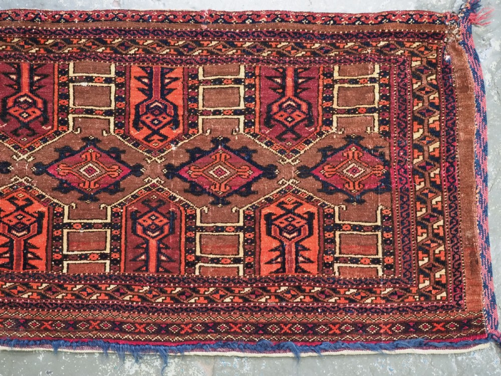 An antique horizontal Saryk Turkmen torba face featuring geometric Kedjebe motifs woven in deep red, dark brown, and cream wool tones. View V