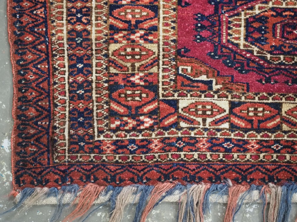 An antique rectangular Tekke Turkmen torba face featuring three central octagonal Salor guls on a deep red wool field with geometric borders and lower fringe. View VII