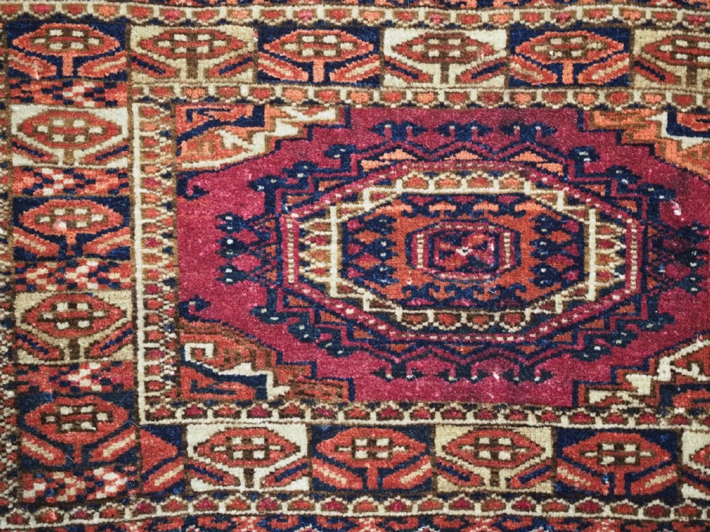 An antique rectangular Tekke Turkmen torba face featuring three central octagonal Salor guls on a deep red wool field with geometric borders and lower fringe. View VIII