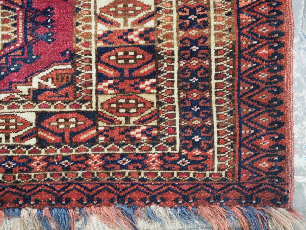 An antique rectangular Tekke Turkmen torba face featuring three central octagonal Salor guls on a deep red wool field with geometric borders and lower fringe. View XI