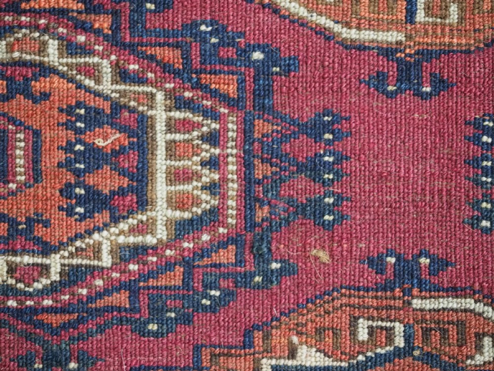 An antique rectangular Tekke Turkmen torba face featuring three central octagonal Salor guls on a deep red wool field with geometric borders and lower fringe. View XII