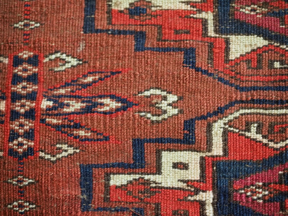 A horizontal rectangular handwoven wool Tekke Turkmen torba bag featuring nine geometric gul motifs in red, navy, and ivory, complete with a long hanging wool fringe at the base. View XIV