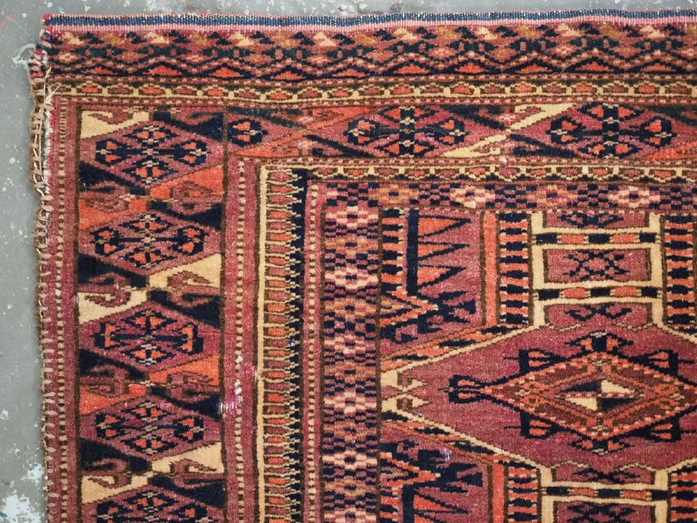 An antique rectangular hand-knotted wool Saryk Turkmen torba face displaying geometric diamond medallions in red, terracotta, and navy shades with lower fringe detail. View VI
