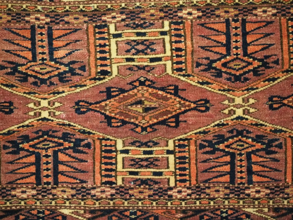 An antique rectangular hand-knotted wool Saryk Turkmen torba face displaying geometric diamond medallions in red, terracotta, and navy shades with lower fringe detail. View VIII