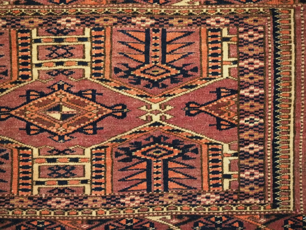An antique rectangular hand-knotted wool Saryk Turkmen torba face displaying geometric diamond medallions in red, terracotta, and navy shades with lower fringe detail. View IX