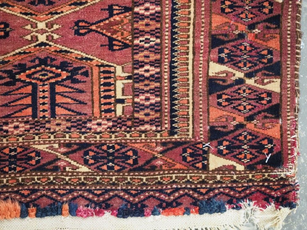 An antique rectangular hand-knotted wool Saryk Turkmen torba face displaying geometric diamond medallions in red, terracotta, and navy shades with lower fringe detail. View XI