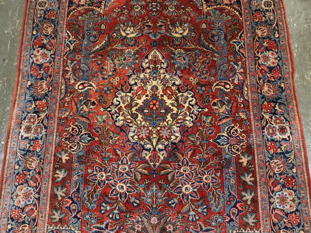 A hand-knotted wool Kashan prayer rug featuring a central floral medallion, a mihrab arch design, and intricate botanical borders in red, navy blue, and cream hues. View III