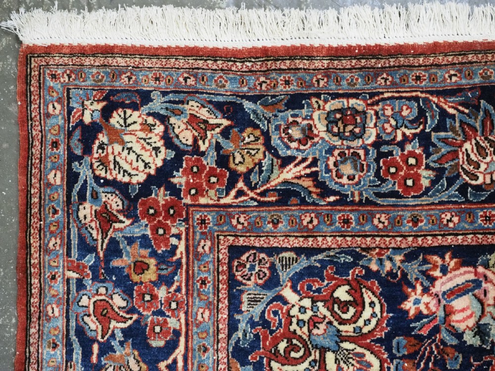 A hand-knotted wool Kashan prayer rug featuring a central floral medallion, a mihrab arch design, and intricate botanical borders in red, navy blue, and cream hues. View IV
