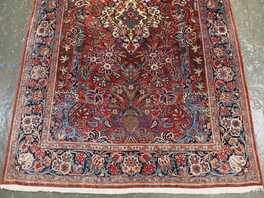 A hand-knotted wool Kashan prayer rug featuring a central floral medallion, a mihrab arch design, and intricate botanical borders in red, navy blue, and cream hues. View V