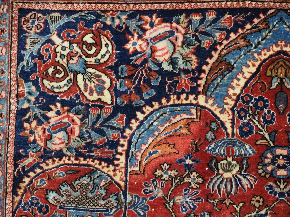 A hand-knotted wool Kashan prayer rug featuring a central floral medallion, a mihrab arch design, and intricate botanical borders in red, navy blue, and cream hues. View VIII