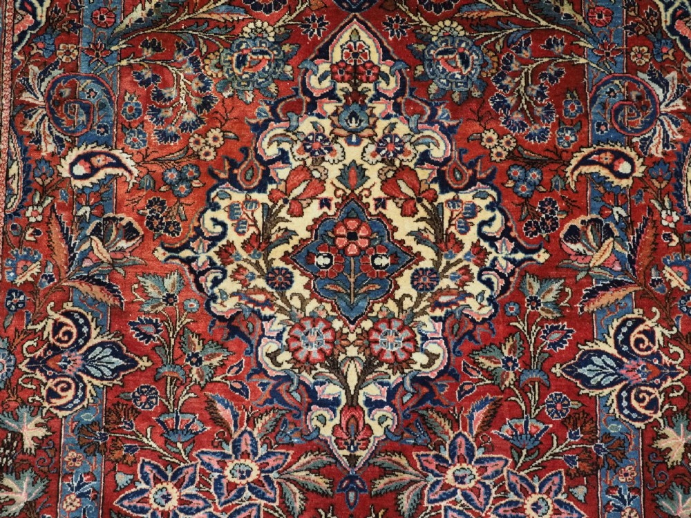 A hand-knotted wool Kashan prayer rug featuring a central floral medallion, a mihrab arch design, and intricate botanical borders in red, navy blue, and cream hues. View X