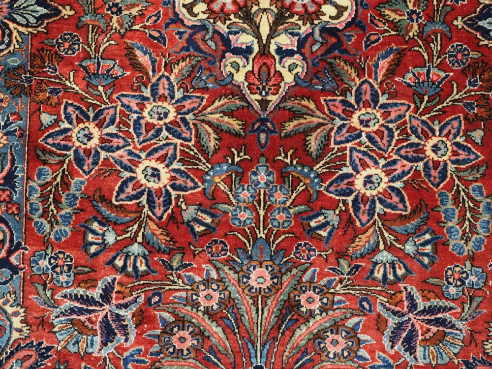 A hand-knotted wool Kashan prayer rug featuring a central floral medallion, a mihrab arch design, and intricate botanical borders in red, navy blue, and cream hues. View XII