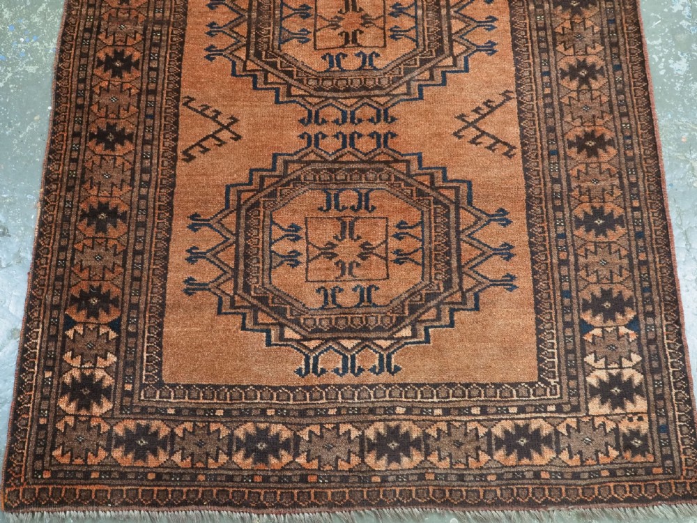 An antique long hand-knotted wool rug featuring four large central turreted octagonal guls on a terracotta field with geometric borders. View VI