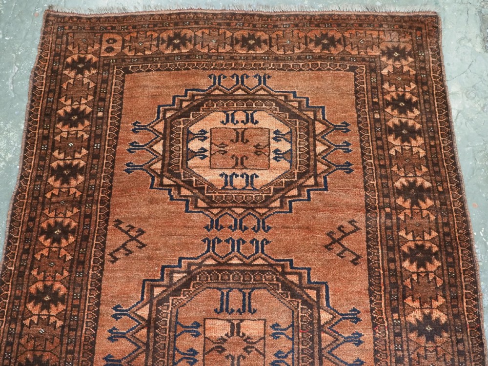 An antique long hand-knotted wool rug featuring four large central turreted octagonal guls on a terracotta field with geometric borders. View VII