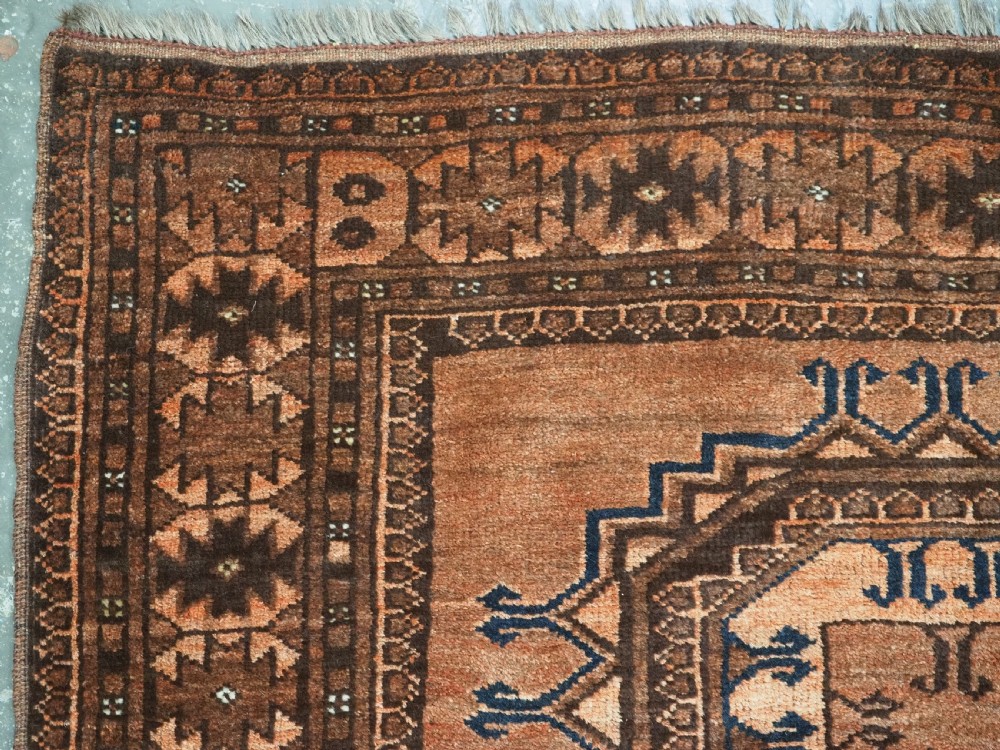 An antique long hand-knotted wool rug featuring four large central turreted octagonal guls on a terracotta field with geometric borders. View VIII