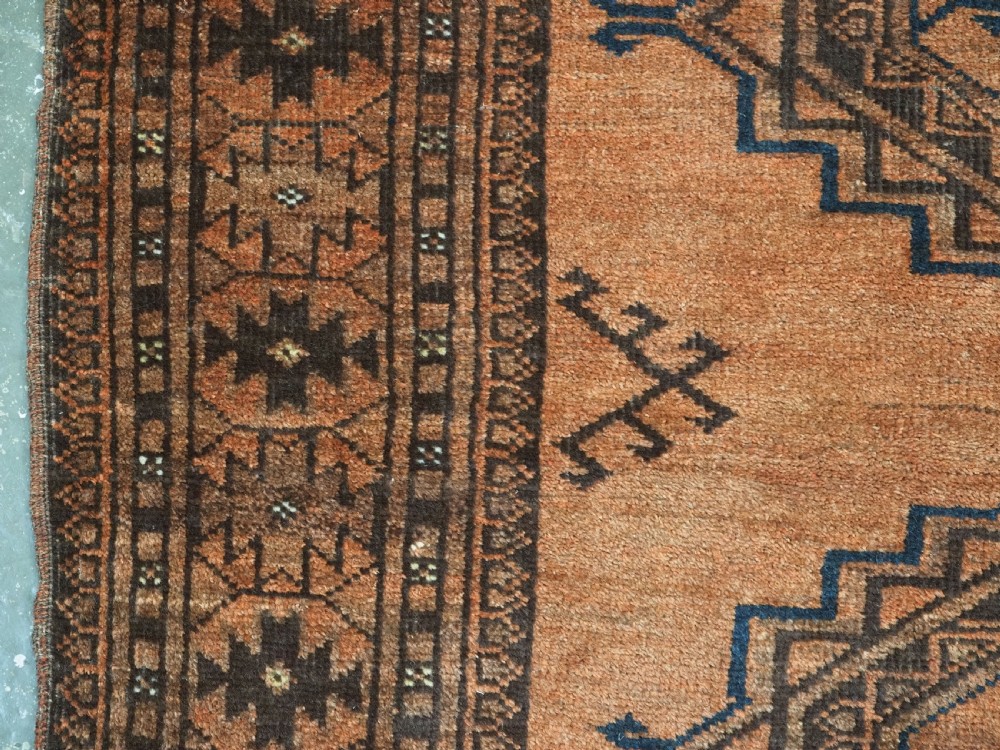 An antique long hand-knotted wool rug featuring four large central turreted octagonal guls on a terracotta field with geometric borders. View IX