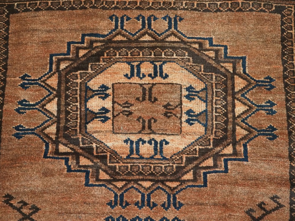 An antique long hand-knotted wool rug featuring four large central turreted octagonal guls on a terracotta field with geometric borders. View X