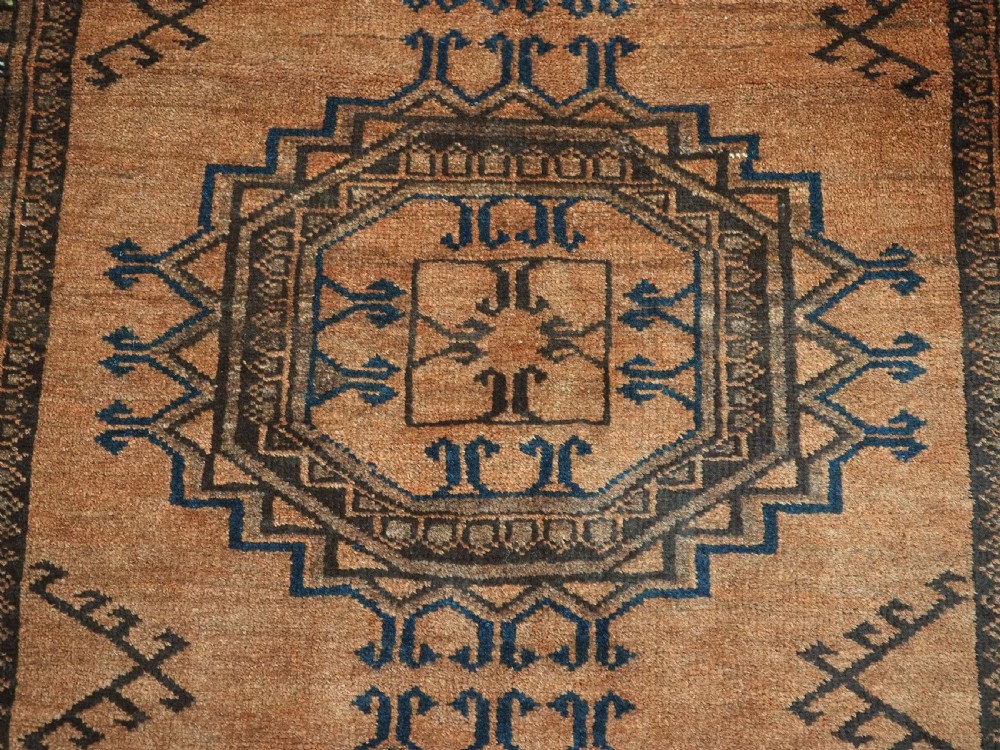 An antique long hand-knotted wool rug featuring four large central turreted octagonal guls on a terracotta field with geometric borders. View XII