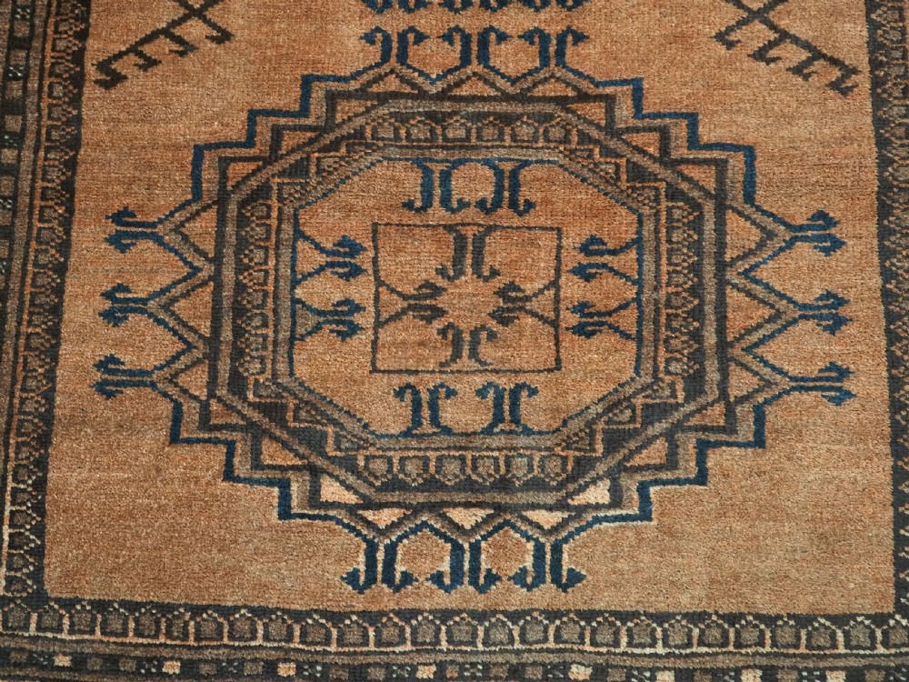 An antique long hand-knotted wool rug featuring four large central turreted octagonal guls on a terracotta field with geometric borders. View XIII