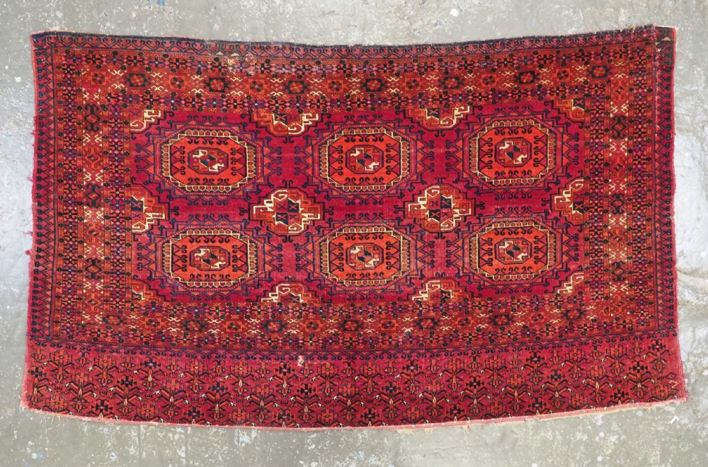 An antique Tekke Turkmen chuval face textile featuring six octagonal turreted guls framed by geometric borders in deep red, navy, and cream wool. View II
