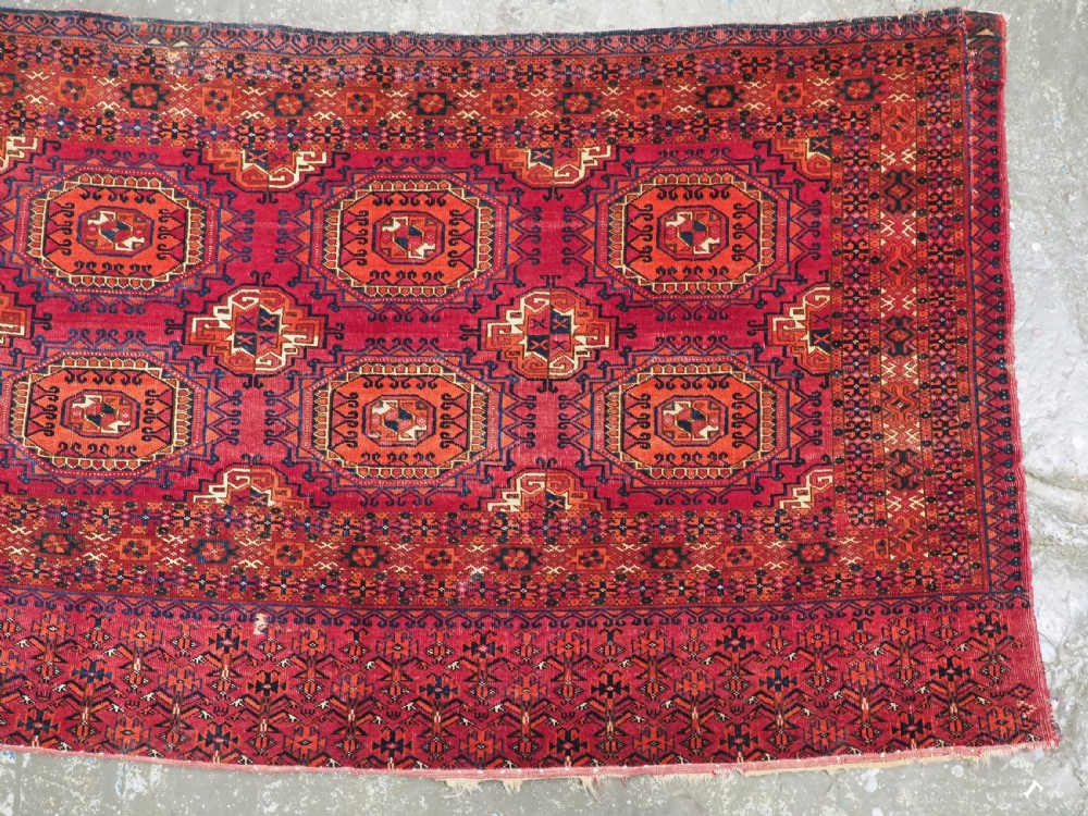 An antique Tekke Turkmen chuval face textile featuring six octagonal turreted guls framed by geometric borders in deep red, navy, and cream wool. View V