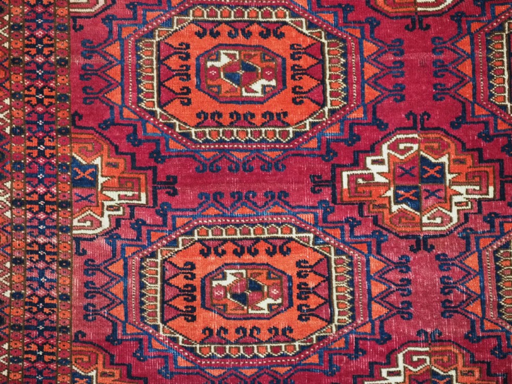 An antique Tekke Turkmen chuval face textile featuring six octagonal turreted guls framed by geometric borders in deep red, navy, and cream wool. View IX