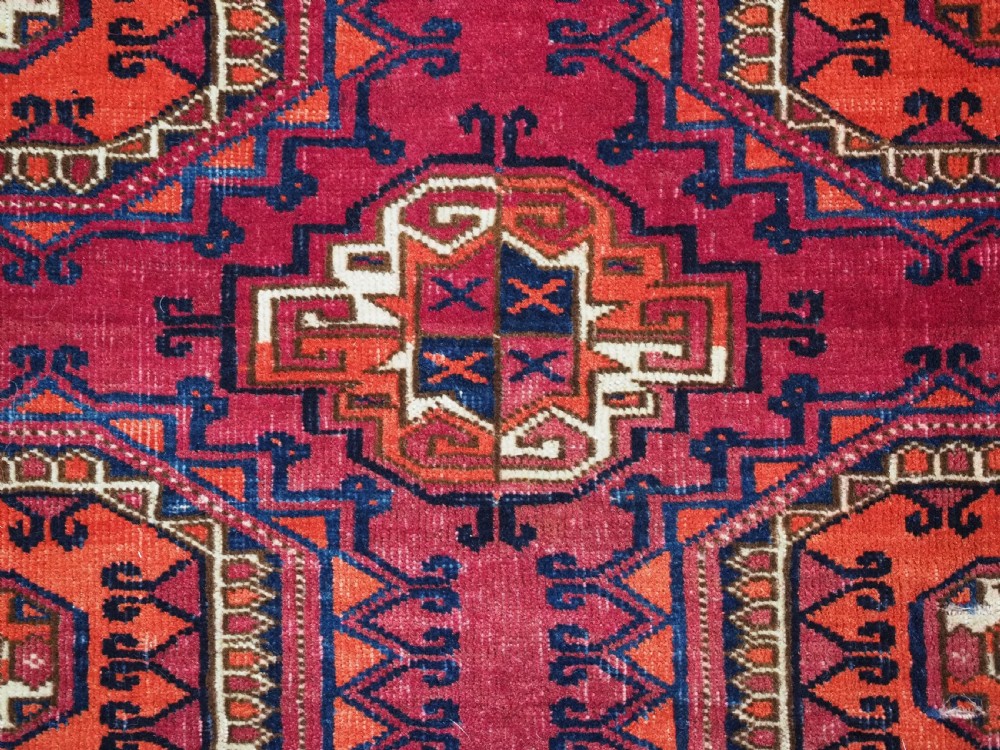 An antique Tekke Turkmen chuval face textile featuring six octagonal turreted guls framed by geometric borders in deep red, navy, and cream wool. View X